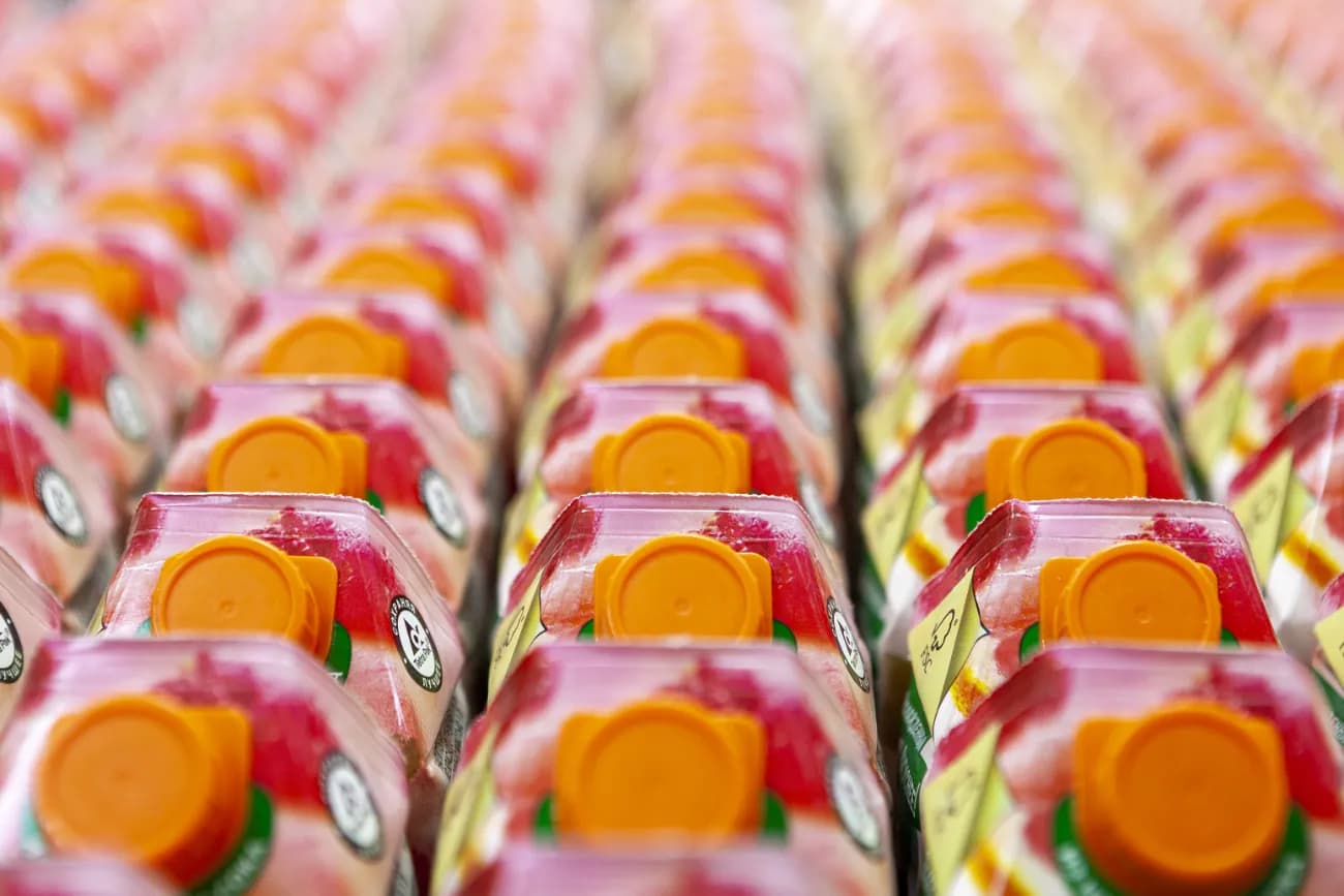 Tightly packed rows of juice cartons with orange caps.