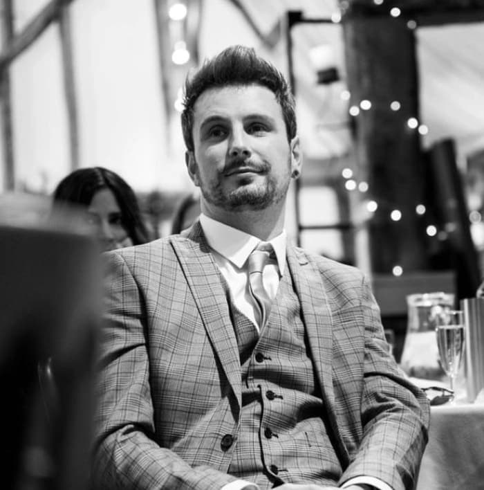 Daniel Jones, seated, in a checked three-piece suit.